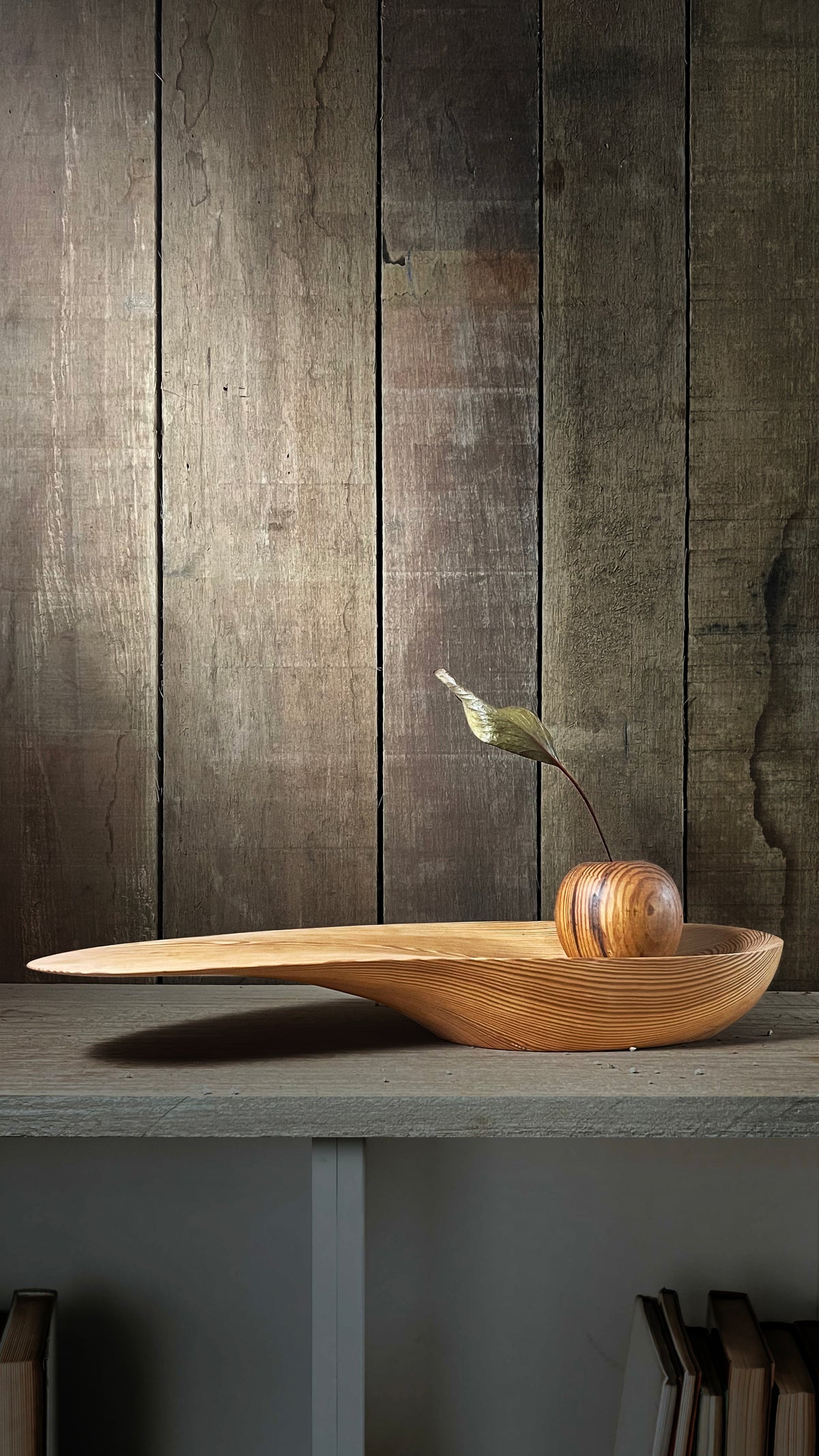 Peca autoral em Pinho de Riga - Blog Diarios do Atelier | O Designer Artesao: Escultura decorativa composta por uma tigela/bandeja rasa e alongada e uma esfera, ambas de madeira torneada, abrigando delicadamente uma folha seca.